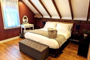 - une chambre avec un grand lit avec un pouf et un miroir dans l'établissement Walkable Elmwood Cottage, No Chores 2Bath 2BR 2Car, à Buffalo
