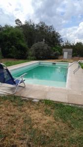 a swimming pool with a lawn chair at Casa de Campo La Querencia in Mercedes