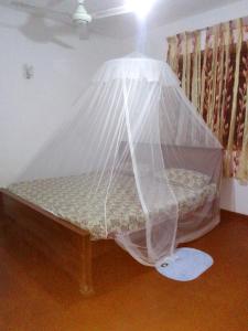 Una cama con una red en una habitación en Tinu Homestay en Mirissa