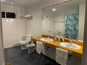 een badkamer met 2 wastafels, een toilet en een spiegel bij Manureva Nui Hotel Boutique in Hanga Roa
