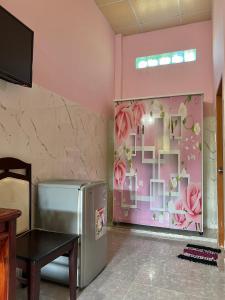 Habitación con nevera y pared con flores en Duc Thao Guest House, en Mui Ne