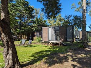 a cabin in the woods with a picnic table and chairs at Tiny House 18 at Grampians Edge in Dadswells Bridge