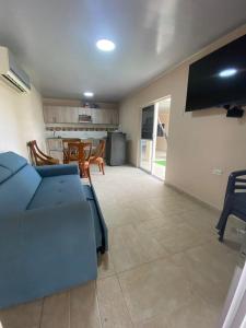 uma sala de estar com um sofá azul e uma cozinha em CABAÑA LUJOSA CON MESA DE BILLAR em Sabanagrande
