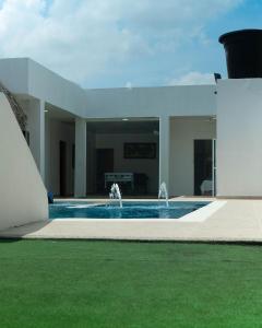uma casa branca com piscina e fonte em CABAÑA LUJOSA CON MESA DE BILLAR em Sabanagrande