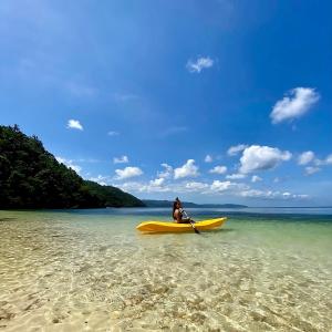 uma pessoa sentada num caiaque amarelo numa praia em Tuburan Cove Beach Resort em Buruanga