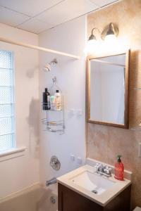 a bathroom with a sink and a mirror and a tub at Comfortable 3 BR Craftsman Bungalow in Milwaukee's Bay View Neighborhood in Milwaukee