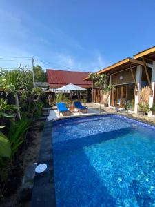 une piscine avec deux chaises bleues et une maison dans l'établissement SUN RESORT GILI TRAWANGAN, à Gili Trawangan