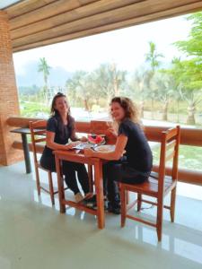 Dos mujeres sentadas en una mesa en una habitación en Vang Vieng Romantic Place Resort en Vang Vieng