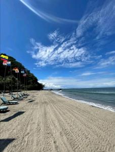 una spiaggia sabbiosa con sedie e bandiere di Casa de Diamantes a Tela
