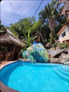 a swimming pool with a large rock next to a house at Casa de Diamantes in Tela