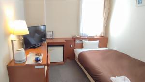 宇多津にある宇多津 グランド ホテルのベッドとテレビが備わるホテルルームです。