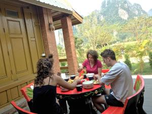 un groupe de personnes assises autour d'une table sur un patio dans l'établissement Vang Vieng Romantic Place Resort, à Vang Vieng