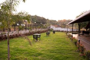 Bliss Nirvana Resort في لونافالا: حديقة بها طاولات وكراسي على العشب