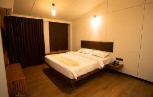 a bedroom with a large white bed with a window at Bliss Nirvana Resort in Lonavala