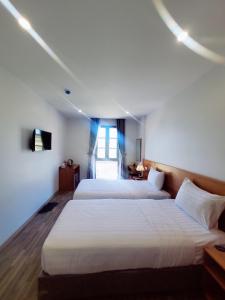 um quarto de hotel com duas camas e uma janela em Sunrise Hotel em Phu Quoc