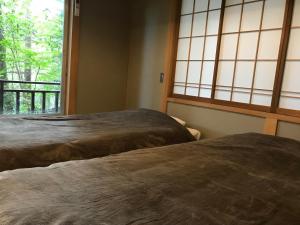 two beds in a room with a window at 天然温泉が満喫できる一棟貸宿 little villa 柊日 in Azumino