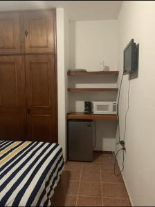 a bedroom with a bed and a desk with a microwave at VILLAS IXCHEL in Tapachula