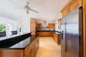 a kitchen with wooden cabinets and a stainless steel refrigerator at Royal Westmoreland - Ocean Drive 8 villa in Saint James
