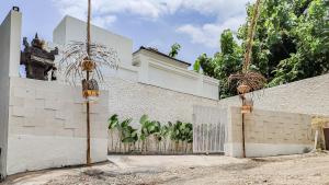 a white building with a gate and a fence at Calm Woods Villa Near Pandawa Beach in Nusa Dua
