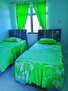 2 camas en una habitación con cortinas verdes en HOTEL ANANDA, 