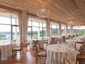 un salón de banquetes con mesas y sillas blancas y ventanas en Shima Kanko Hotel The Classic, en Shima