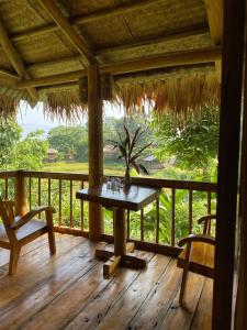 Chez Thuc Home’stay في Thanh Hóa: شرفة خشبية مع طاولة وكرسيين