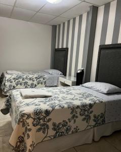 two beds in a room with striped walls at Hostal Rio Piedra in Estelí