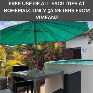 una mesa con una sombrilla verde junto a una piscina en Vimeanz @Bohemiaz, en Kampot