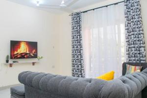 een grijze bank in een woonkamer met een tv bij Nyali Sea View 4 Beds Apartment With Pool in Mombasa