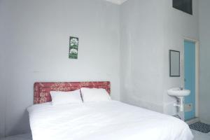 a bedroom with a white bed with a red headboard at Hotel O Pondok Bintang in Kendari