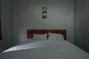 a bed with two pillows and a picture on the wall at Hotel O Pondok Bintang in Kendari
