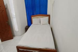 a small bed in a room with a blue curtain at Hotel O Pondok Bintang in Kendari