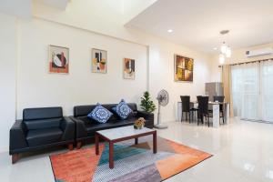 uma sala de estar com um sofá preto e uma mesa em AreeHouse 曼谷 300平方 獨棟別墅 家庭首選 近7-11 BigC MRT em Bangkok