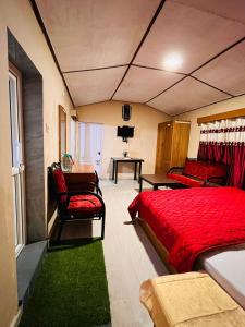 um quarto com uma cama vermelha, 2 cadeiras e uma secretária em Brickhouse em Kodaikanal