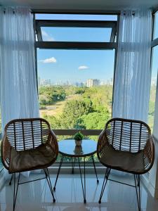 two chairs and a table in front of a window at 2br Golfcourse view near airport in Manila