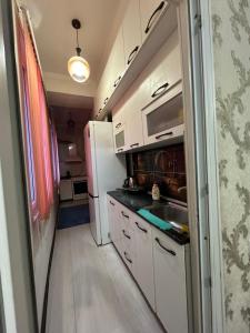 een keuken met witte kasten en een witte koelkast bij Center Cozy Apartment in Bisjkek