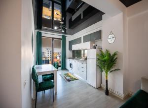 a kitchen with white cabinets and a table and a plant at TAN de LUX in Mamaia Sat/Năvodari
