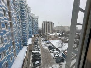 een uitzicht op een parkeerplaats met geparkeerde auto's in de sneeuw bij Center Cozy Apartment in Bisjkek