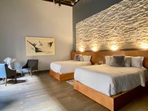 um quarto com 2 camas e uma parede de tijolos em Hotel Plaza D Armas em Querétaro