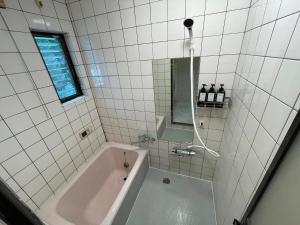 a white tiled bathroom with a tub and a window at 【2024/2月OPEN! 一軒家貸切】東京ディズニーリゾートまで車5分、徒歩20分 in Tokyo