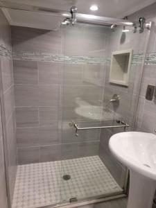 una ducha con una puerta de cristal junto a un lavabo en The Subterranean Haven en Mount Vernon