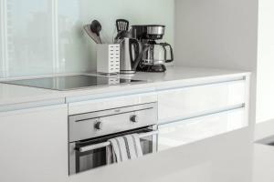 a white kitchen with a stove and a sink at Downtown condo near Stampede, LRT, free parking & gym in Calgary +32 photos