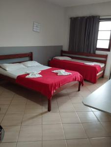 two beds in a room with red sheets at Hotel Pousada Em Guarapari - Pousada Paraiso in Guarapari