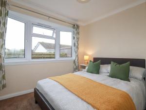 a bedroom with a bed with green pillows and a window at Summer Breeze in Padstow