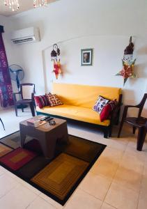 La Hacienda ras sedr chalet في رأس سدر: غرفة معيشة مع أريكة صفراء وطاولة