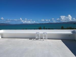 zwei Stühle auf einem Dach mit dem Meer in der Unterkunft 青風 Aokaji 古宇利島のプール付き一棟ヴィラ in Kouri