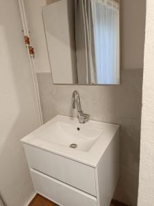 lavabo blanco en el baño con espejo en La Mansio de Bons, en Les Deux Alpes