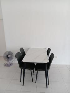 a table with four black chairs and a fan at Dream House in Chemor