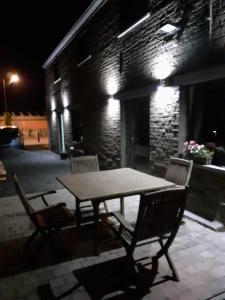 einen Holztisch und Stühle auf einer Terrasse in der Nacht in der Unterkunft Les gîtes du Ravel in Soignies