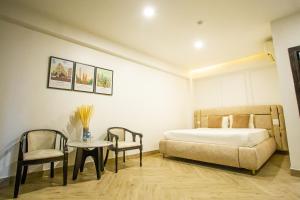 Phuoc Thanh IV Hotel في فينه لونج: غرفة نوم بسرير وطاولة وكراسي
